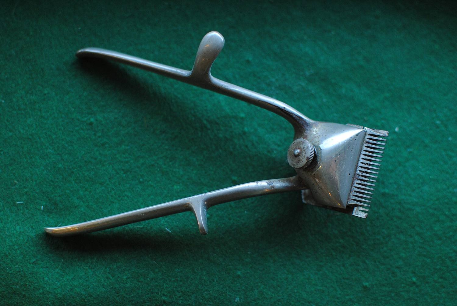An old pair of manual hair clippers on green felt