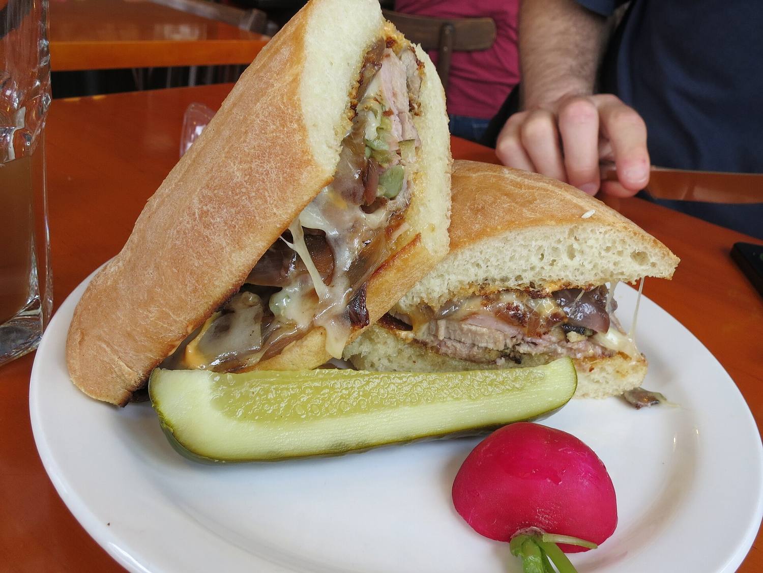 A pressed Cuban sandwich with a pickle on the side