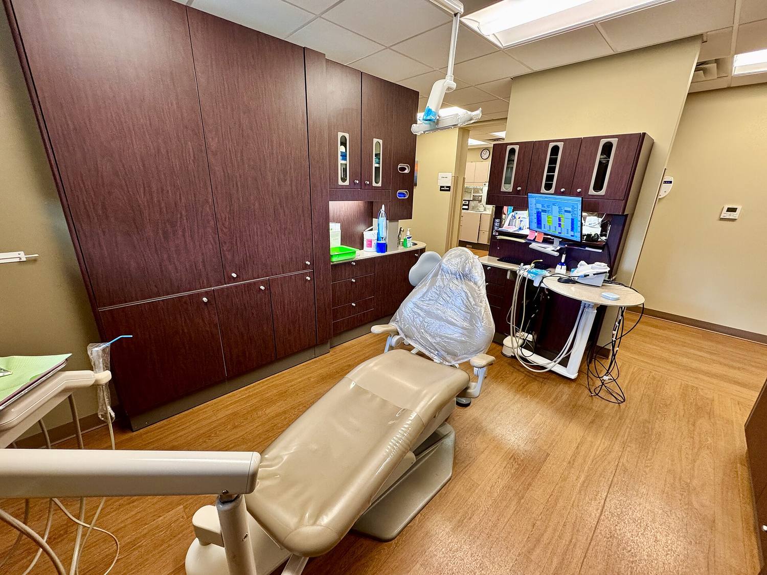 A warm treatment room with a dental chair and wood cabinets
