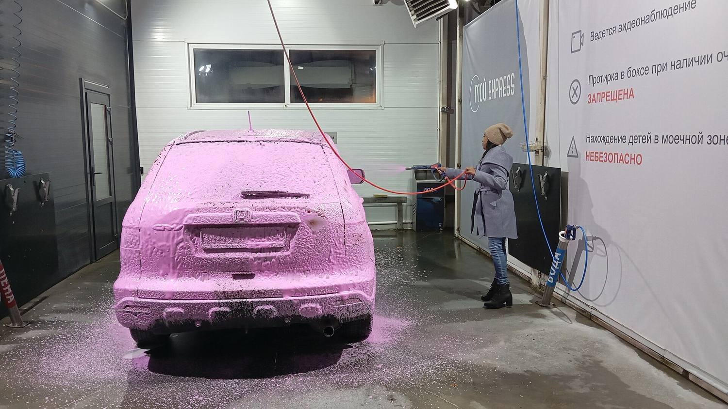 A car covered in pink foam during a wash
