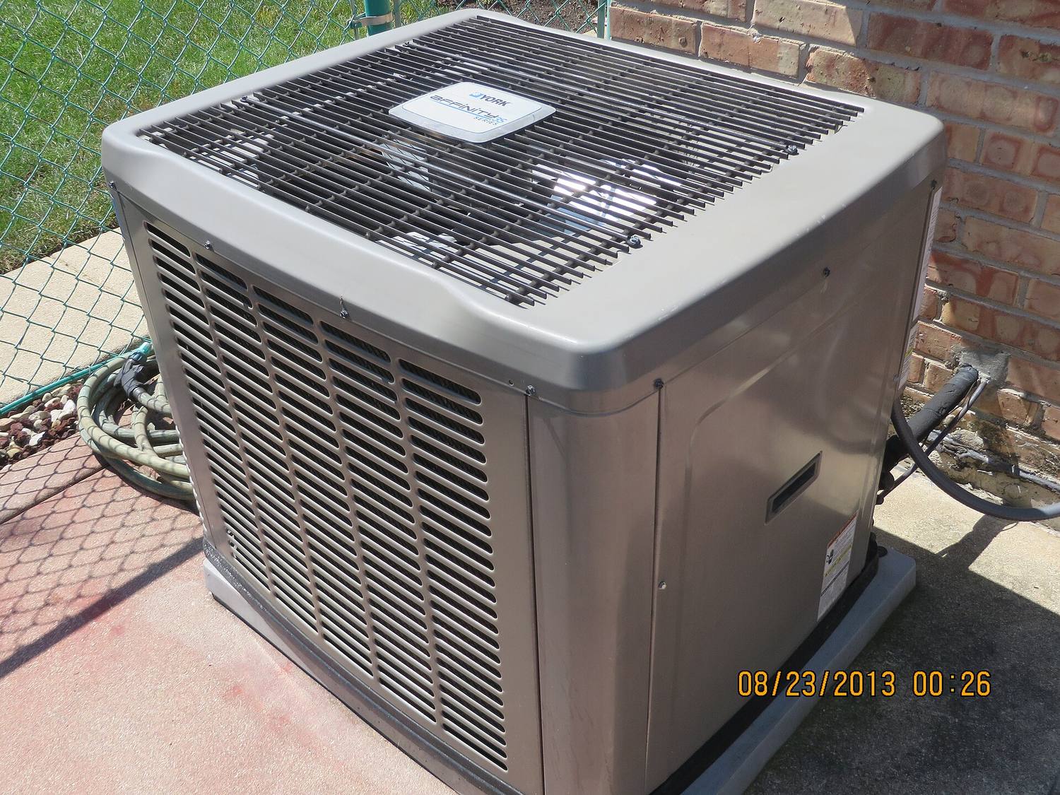 An outdoor air conditioner condenser unit beside a house