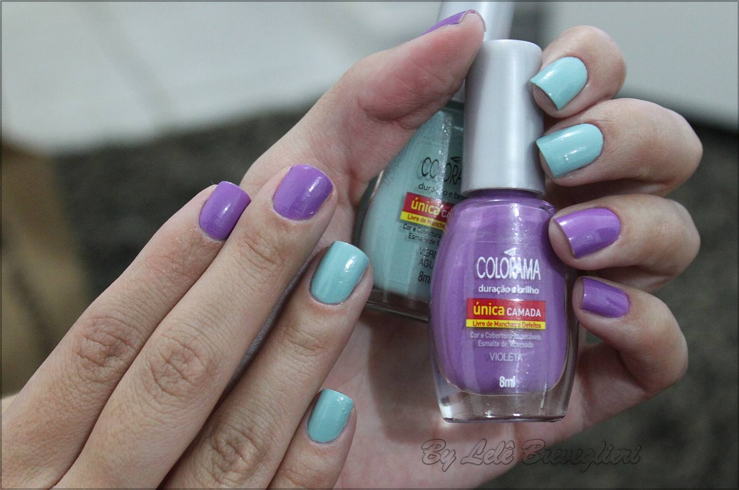 Hands with lilac and mint painted nails holding a bottle of polish