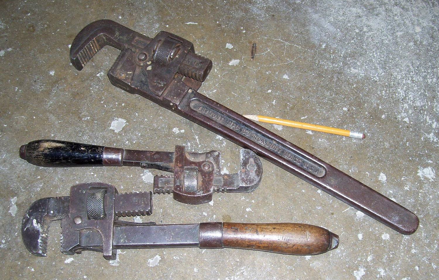 Two old, well-used pipe wrenches on a workbench