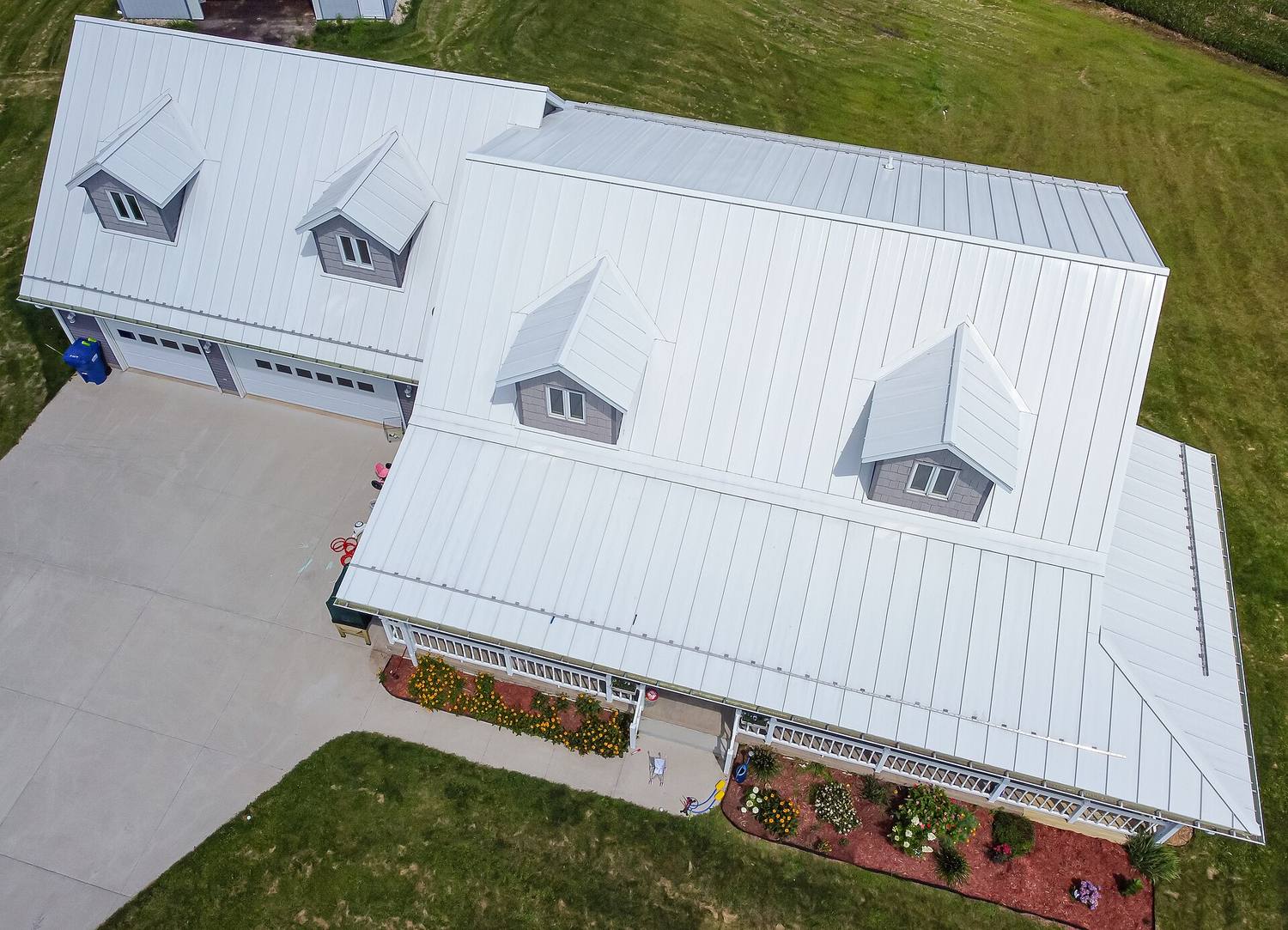 A house with a new white standing-seam metal roof, seen from above