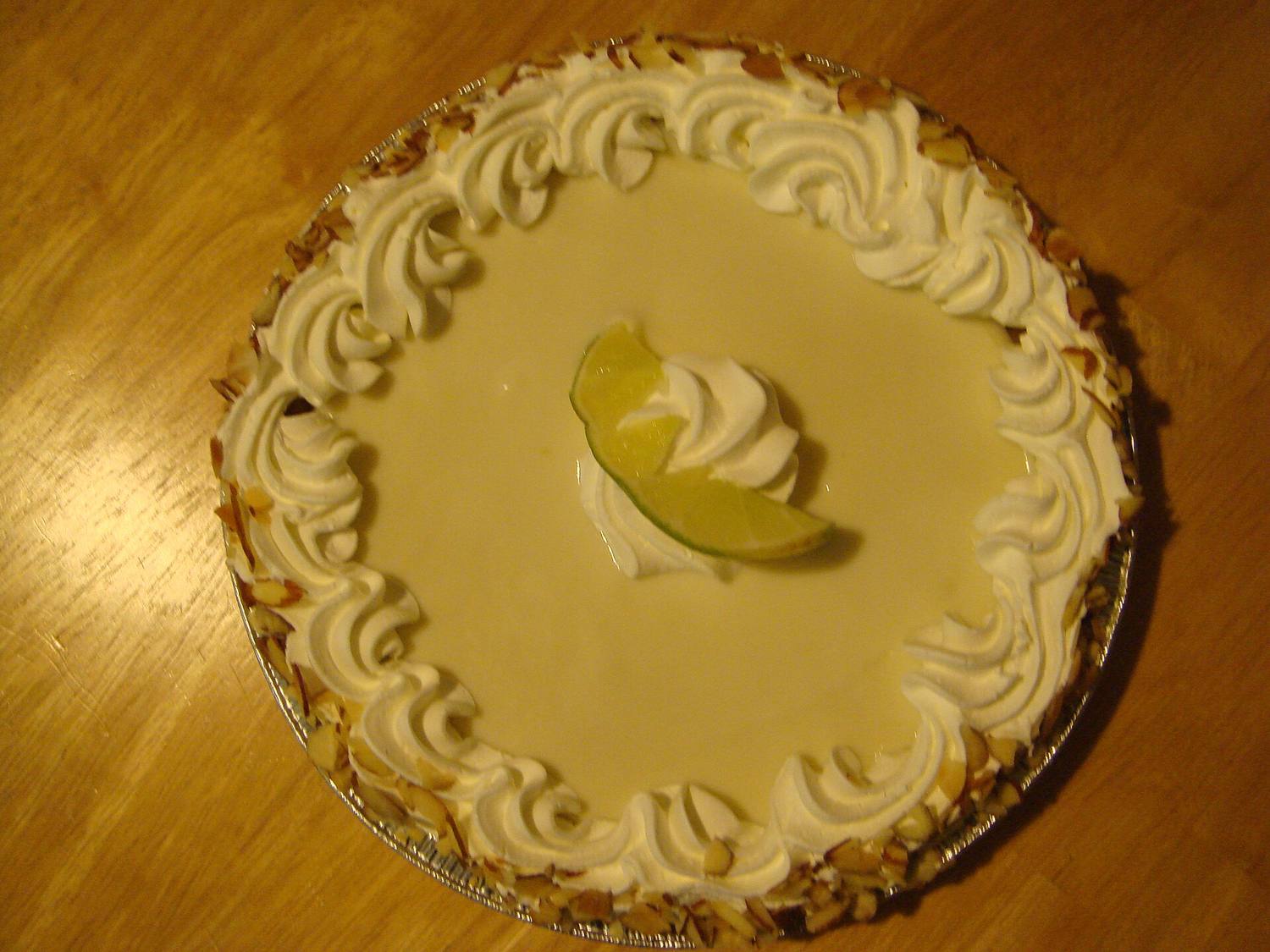 A whole key lime pie with whipped cream and a lime slice