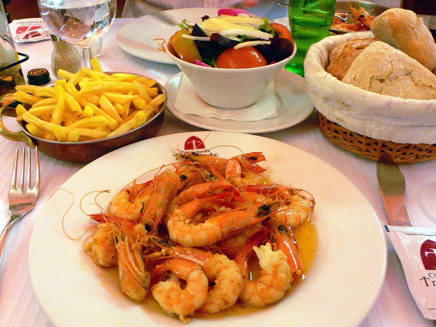 A plate of shrimp with fries and bread on a table
